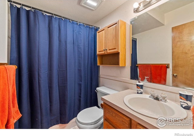 bathroom with vanity, toilet, and tile walls