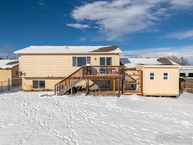 snow covered property with a storage unit and a wooden deck