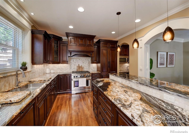 kitchen with dark brown cabinets, pendant lighting, appliances with stainless steel finishes, sink, and dark stone counters