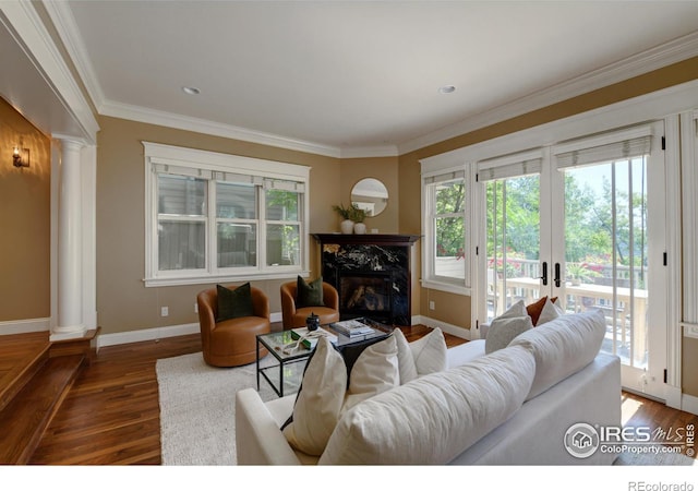 living room featuring crown molding, decorative columns, a premium fireplace, and dark hardwood / wood-style flooring