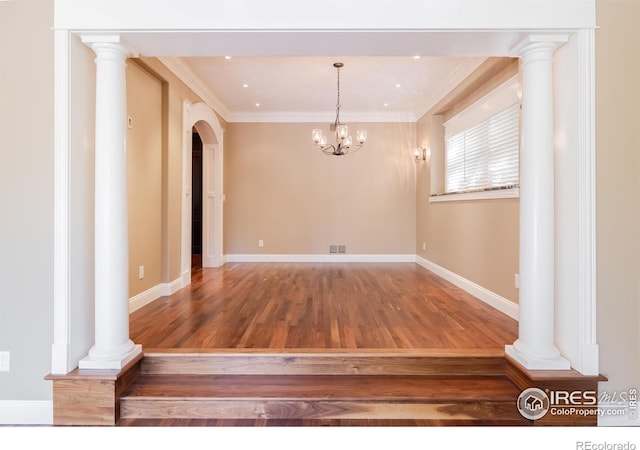 unfurnished dining area with decorative columns, ornamental molding, a notable chandelier, and wood-type flooring