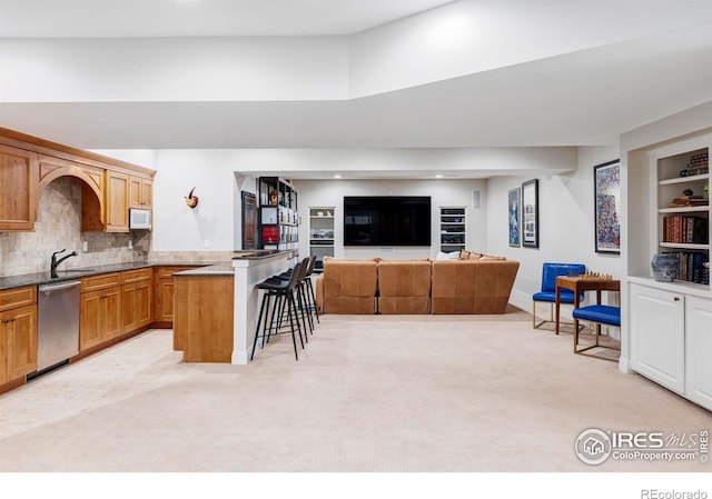 kitchen with dishwasher, light carpet, sink, backsplash, and a breakfast bar area