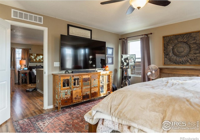 bedroom featuring ceiling fan, dark hardwood / wood-style flooring, and multiple windows