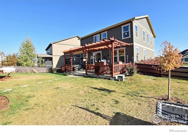 back of house featuring a deck, a lawn, and a pergola