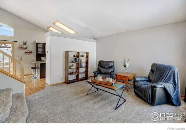 living room featuring carpet, stairs, baseboards, and vaulted ceiling