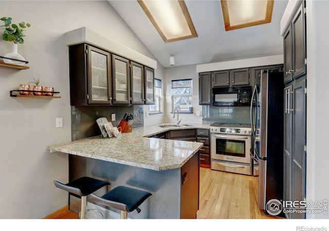 kitchen with stainless steel appliances, decorative backsplash, vaulted ceiling, a sink, and a peninsula