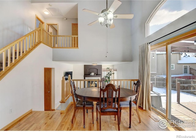 dining room with a towering ceiling, baseboards, a ceiling fan, and wood finished floors