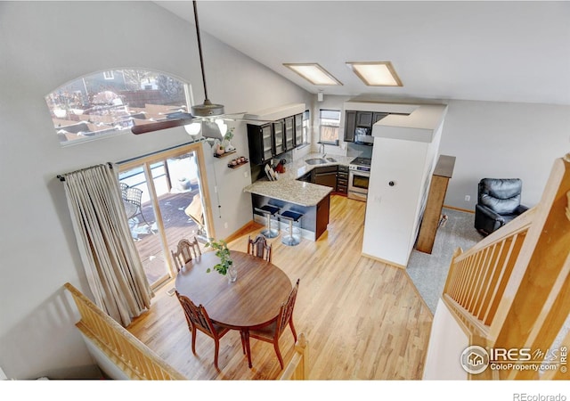 dining room with light wood-style floors, plenty of natural light, vaulted ceiling, and a ceiling fan