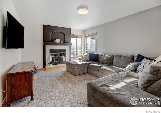 living room featuring a tile fireplace, carpet flooring, and baseboards