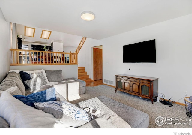 living room with baseboards, stairs, visible vents, and carpet flooring