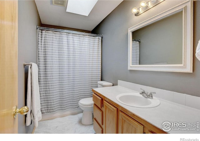 full bathroom with toilet, a skylight, curtained shower, and vanity