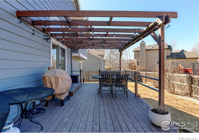 wooden terrace featuring outdoor dining area, grilling area, a fenced backyard, and a pergola