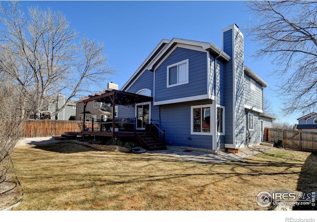 back of house featuring a deck, a yard, a chimney, and fence