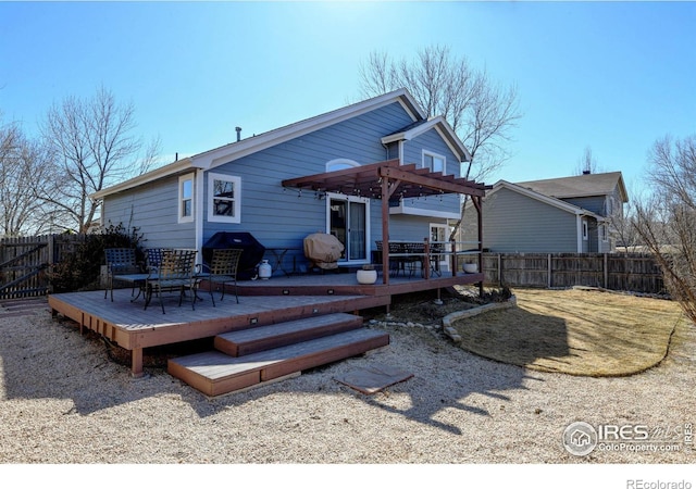 rear view of property with fence, a wooden deck, and a pergola