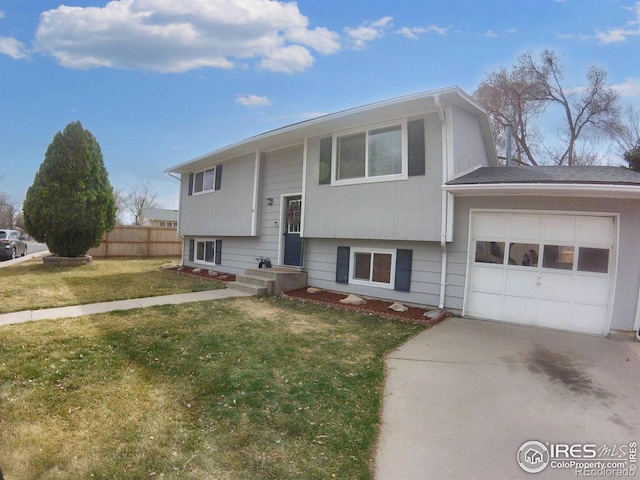 raised ranch with concrete driveway, a front yard, a garage, and fence