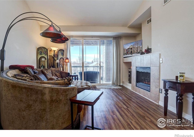 living room with lofted ceiling, a tile fireplace, and dark hardwood / wood-style flooring