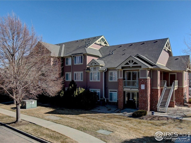 multi unit property featuring stairs and roof with shingles