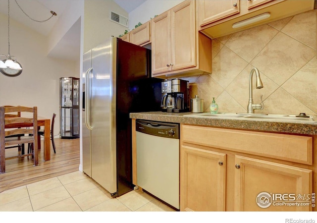 kitchen featuring light tile patterned floors, dishwasher, backsplash, light brown cabinets, and a sink