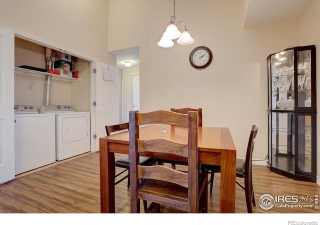 dining area with light wood-style floors, washer and dryer, and a chandelier