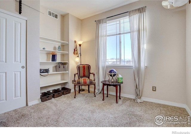 sitting room featuring built in shelves, carpet, visible vents, and baseboards