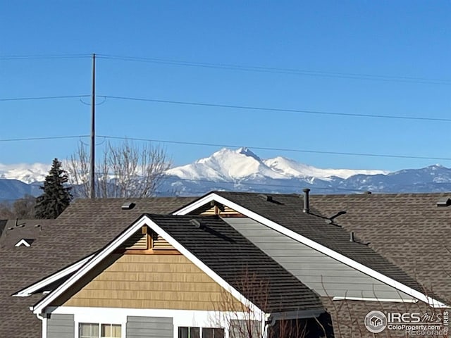 view of side of home featuring a mountain view and roof with shingles