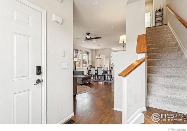 stairs featuring hardwood / wood-style floors and ceiling fan with notable chandelier