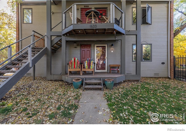 view of front of house featuring a front yard, a balcony, fence, covered porch, and stairs