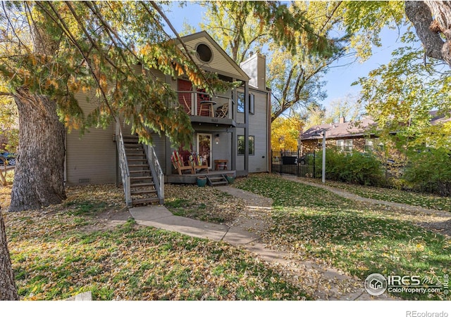 rear view of property with a chimney, fence, a yard, crawl space, and stairs