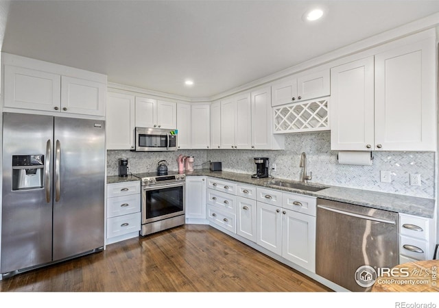 kitchen with a sink, stone countertops, appliances with stainless steel finishes, and white cabinets