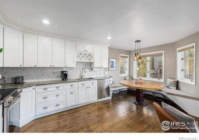 kitchen with backsplash, breakfast area, appliances with stainless steel finishes, white cabinetry, and a sink