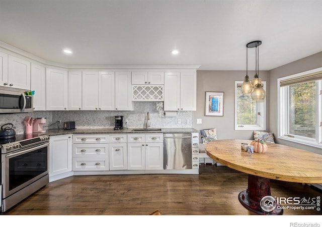 kitchen with tasteful backsplash, decorative light fixtures, stainless steel appliances, white cabinetry, and a sink