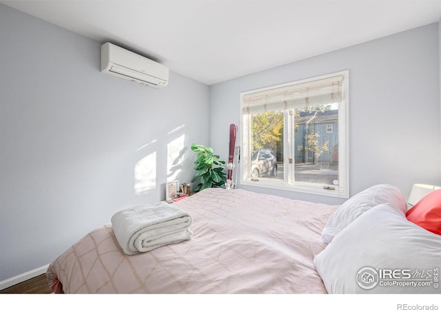 bedroom with baseboards, wood finished floors, and a wall unit AC