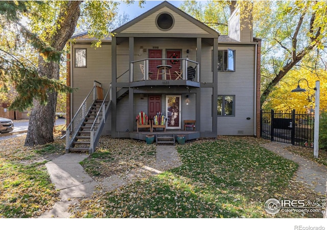 view of front facade featuring a front yard, stairway, fence, and a chimney