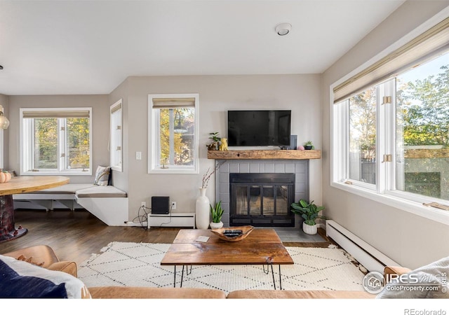 living room featuring wood finished floors, a fireplace, breakfast area, and a baseboard radiator