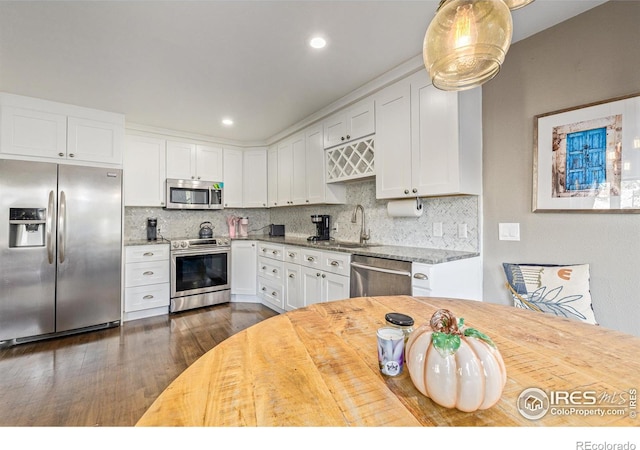 kitchen with a sink, white cabinets, tasteful backsplash, and stainless steel appliances