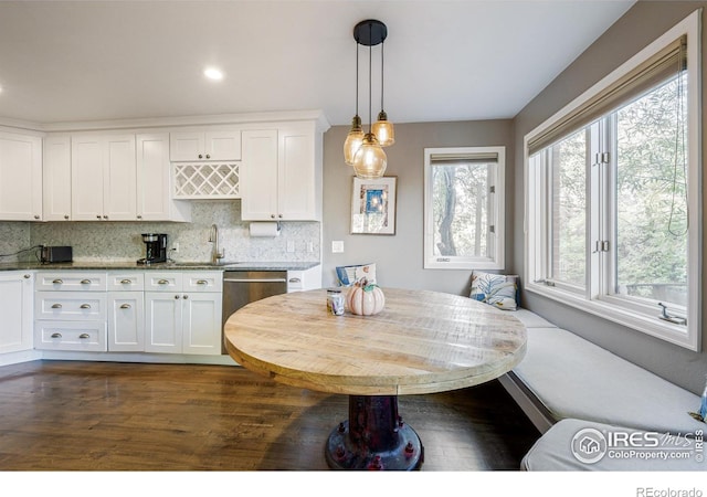 kitchen with dishwasher, breakfast area, decorative backsplash, white cabinets, and a sink