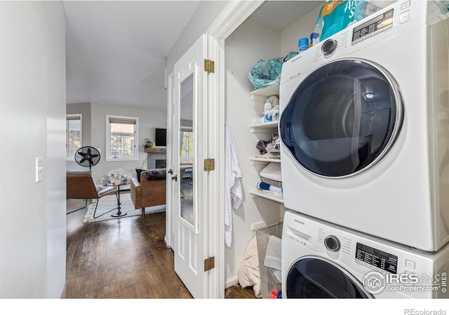 laundry room featuring dark wood-style floors, laundry area, and stacked washer and dryer