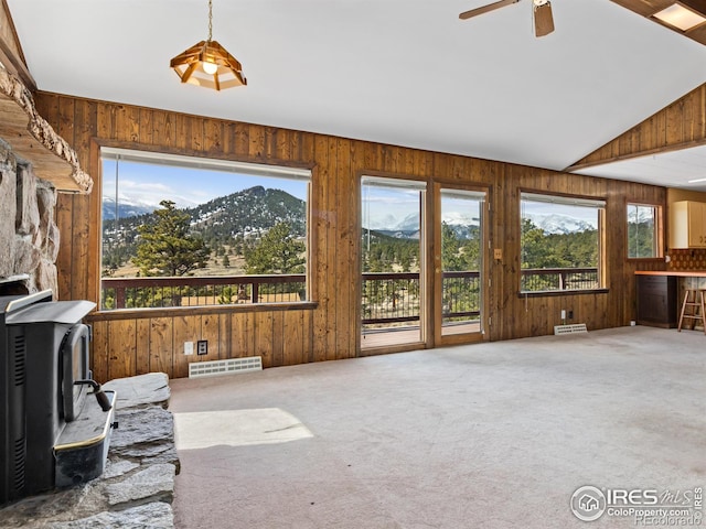 carpeted living room featuring ceiling fan, a wood stove, a mountain view, and lofted ceiling