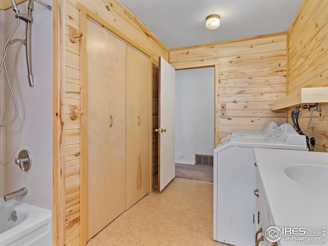 laundry area with washing machine and dryer, wooden walls, and light carpet