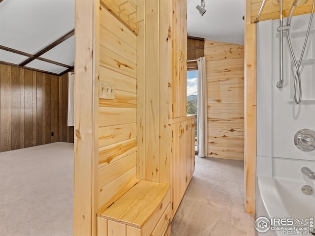 bathroom featuring shower / bath combination and wood walls