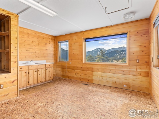 unfurnished room with a mountain view, a wealth of natural light, and wooden walls