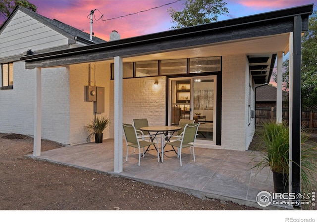 back house at dusk featuring a patio area