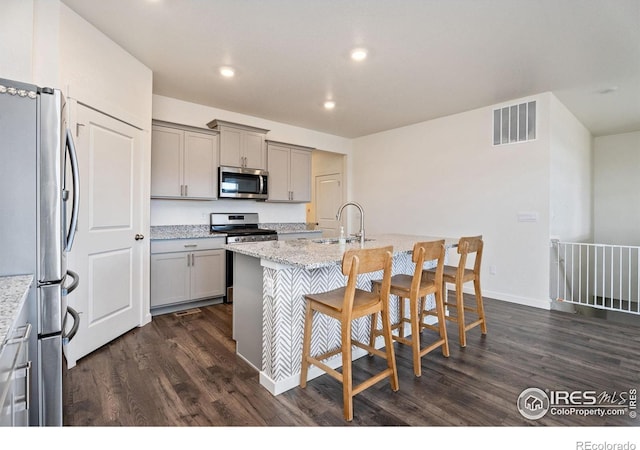 kitchen featuring sink, light stone countertops, appliances with stainless steel finishes, and gray cabinetry