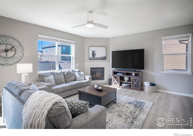 living room featuring ceiling fan, a brick fireplace, and wood-type flooring