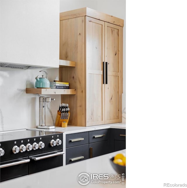 kitchen featuring range with two ovens and light brown cabinetry