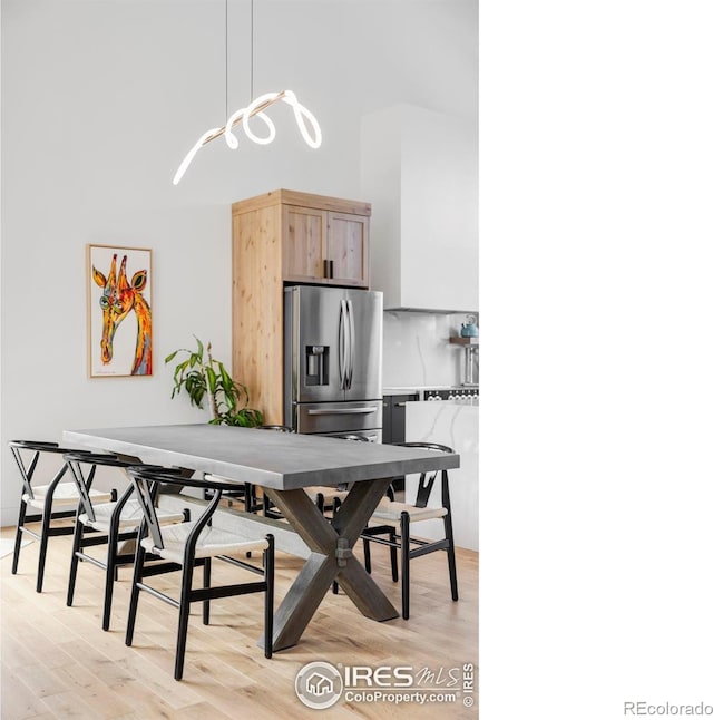 dining area with a towering ceiling and light wood-type flooring