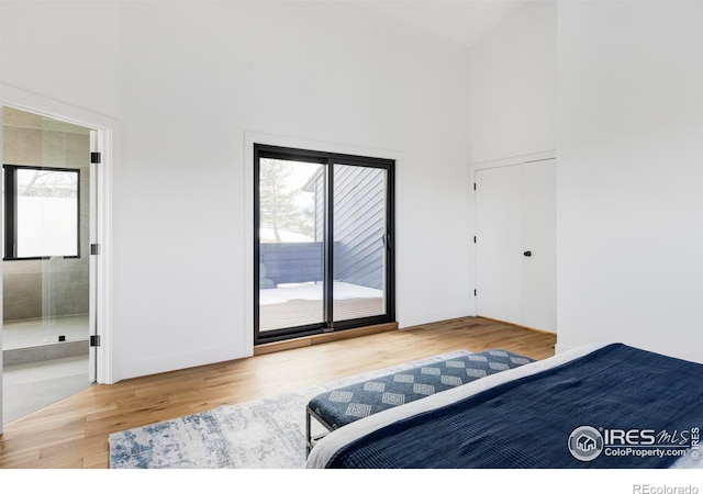 bedroom featuring hardwood / wood-style floors, a towering ceiling, and access to outside