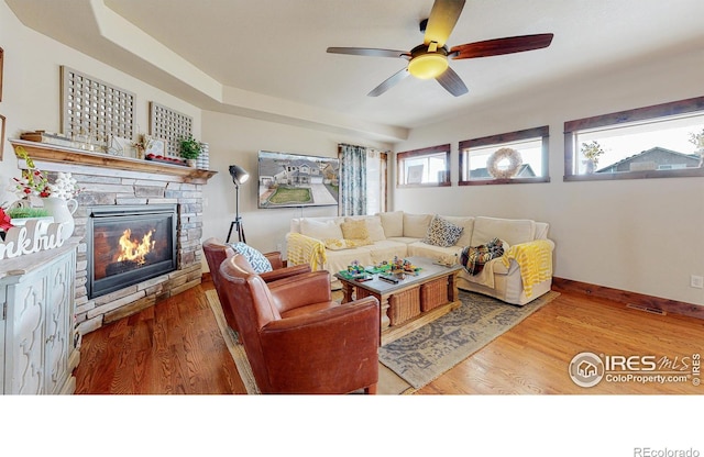 living room featuring hardwood / wood-style flooring, ceiling fan, and a fireplace