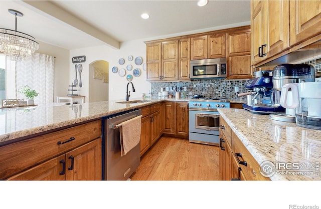 kitchen featuring light stone countertops, appliances with stainless steel finishes, decorative light fixtures, decorative backsplash, and sink