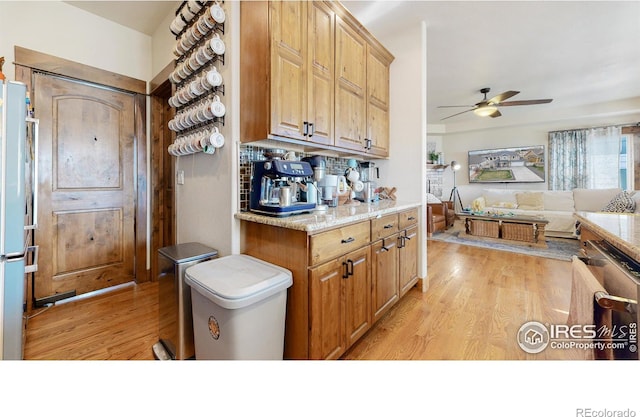 kitchen featuring light wood-type flooring, ceiling fan, light stone countertops, and white fridge